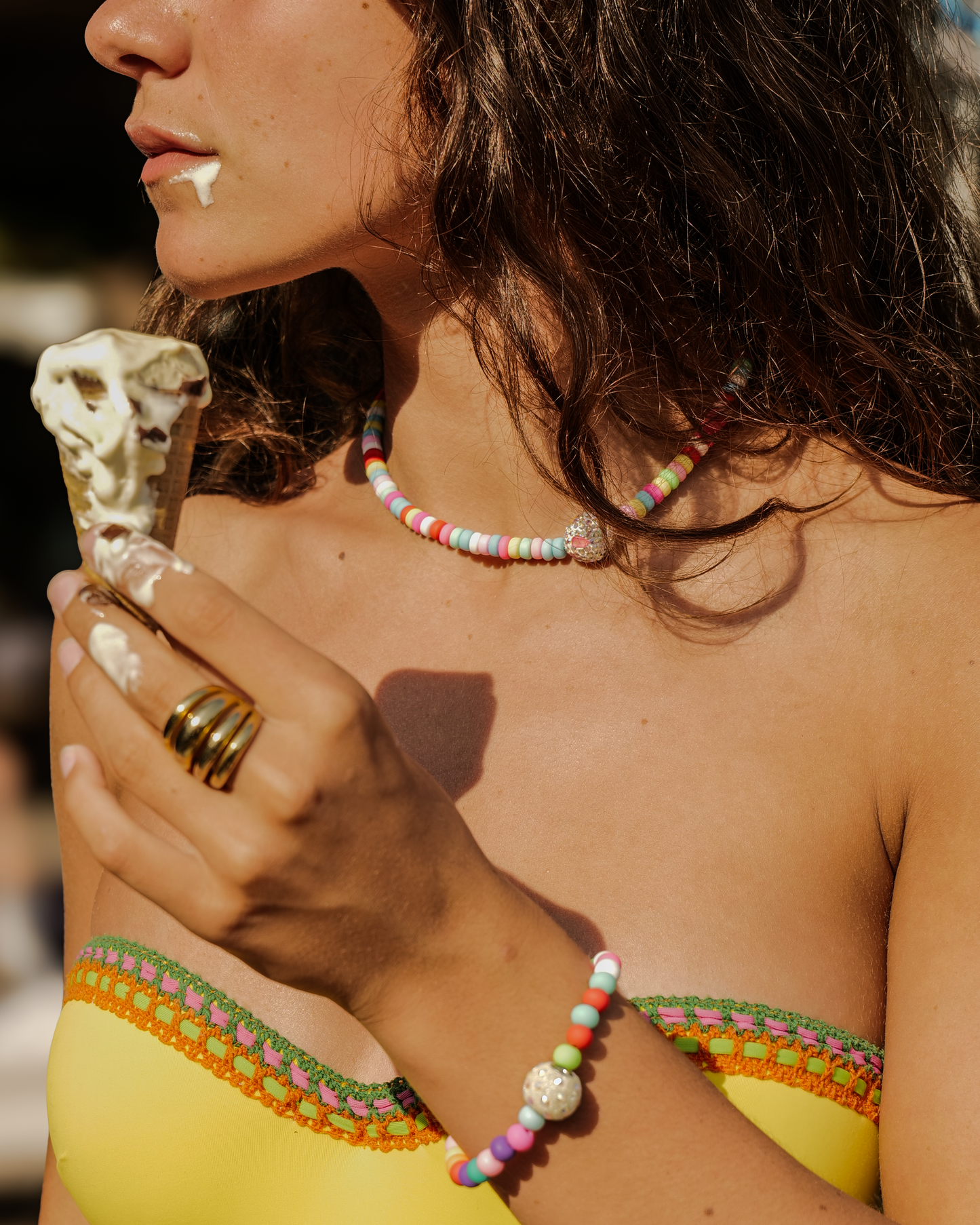 Femme dégustant une glace au soleil, portant le duo Cocktail Acidulé Bourjeone composé d’un collier et d’un bracelet aux perles multicolores.
