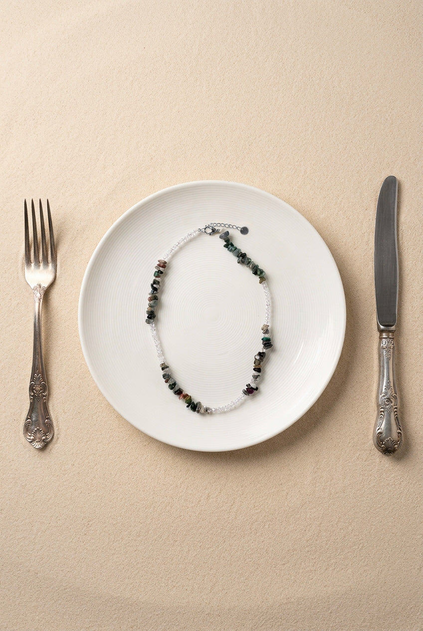 Vue du collier Pistachio sur support noir, mettant en avant les finitions en acier inoxydable doré et les pierres naturelles.