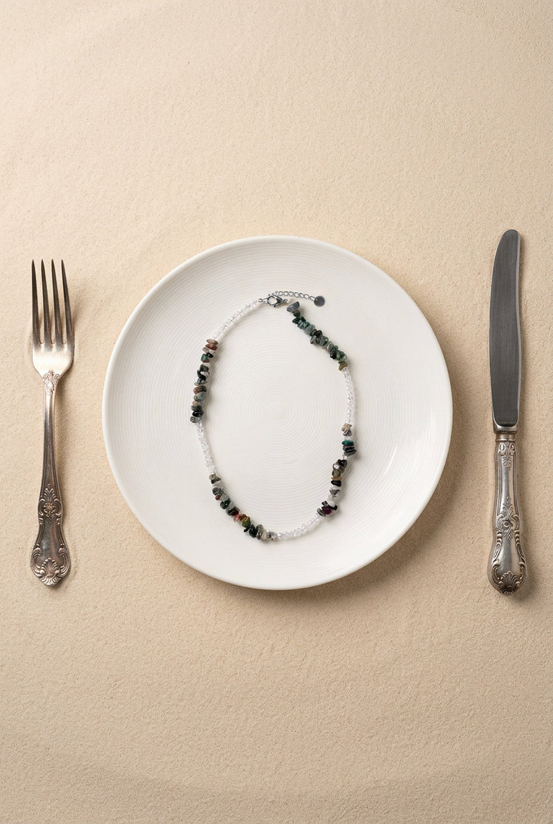 Vue du collier Pistachio sur support noir, mettant en avant les finitions en acier inoxydable doré et les pierres naturelles.