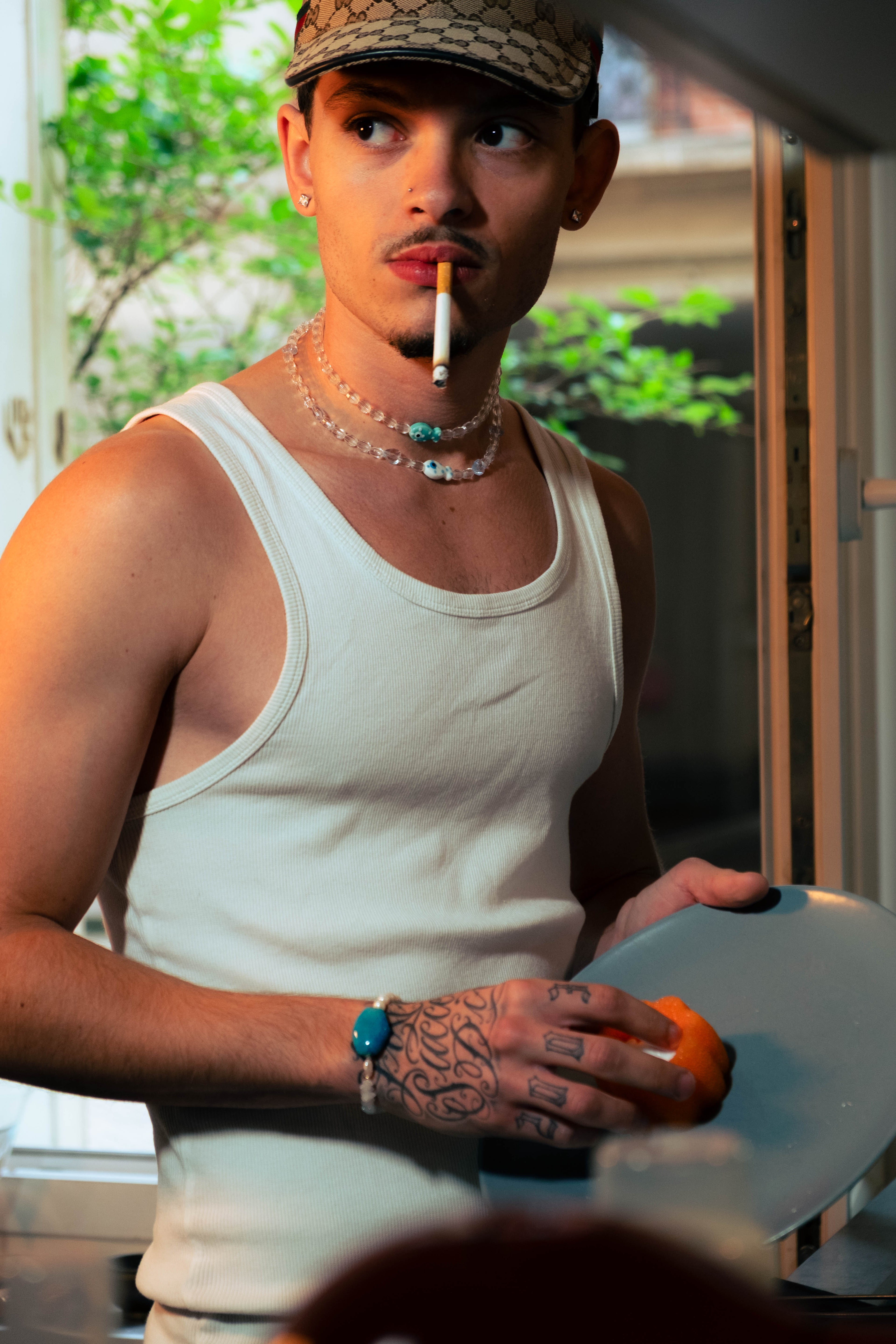 Homme portant deux colliers transparents et un bracelet turquoise Bourjeone tout en lavant la vaisselle.