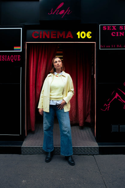 Femme portant un collier coloré Bourjeone devant une entrée de cinéma à Paris, vêtue de jaune.