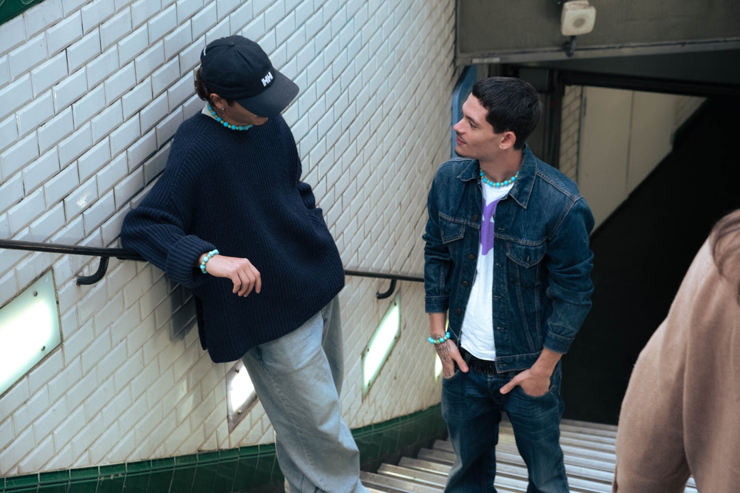 Deux hommes dans le métro parisien portant des colliers et bracelets turquoise Bourjeone.
