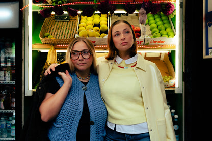 Deux femmes portant des colliers colorés Bourjeone devant un étal de fruits dans un supermarché parisien.