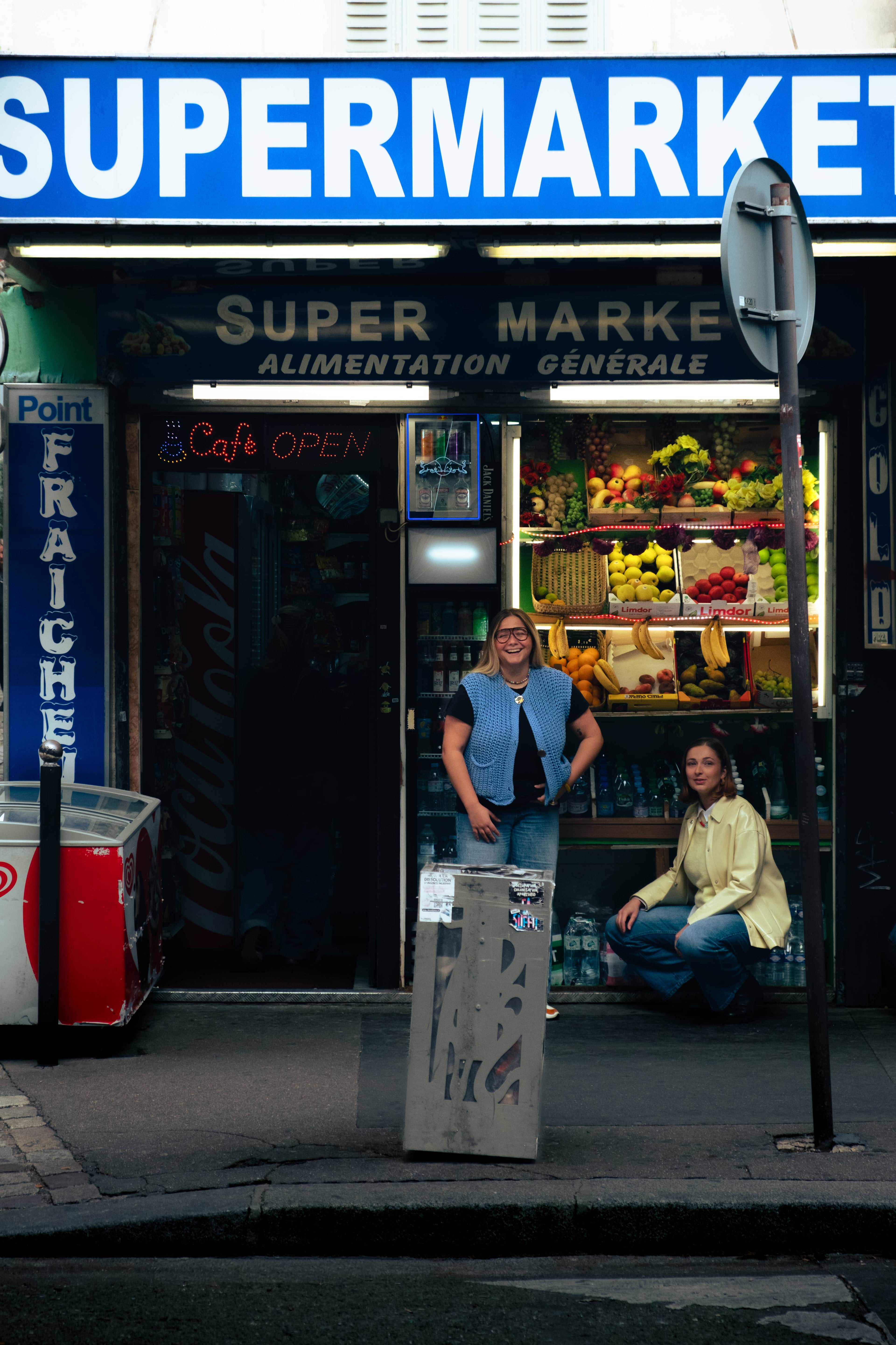 Deux femmes devant un supermarché coloré à Paris portant des bijoux Bourjeone.
