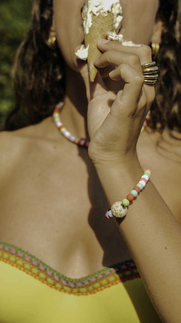 Femme dégustant une glace, portant le bracelet Tutti Frutti Bourjeone aux perles colorées et gourmandes.