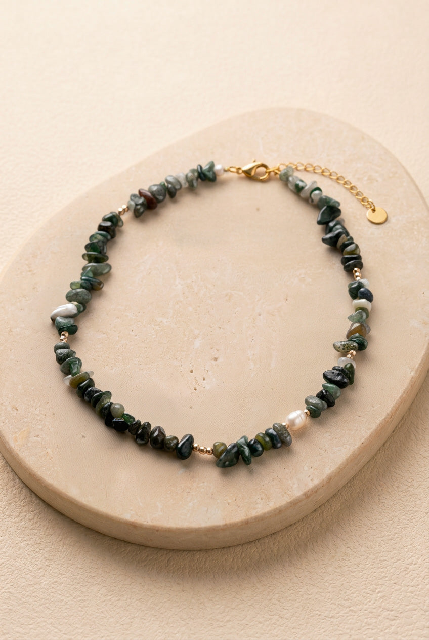 Vue d'ensemble du collier Câpre sur un support noir, détaillant les nuances de vert des pierres et le fermoir en acier inoxydable doré.