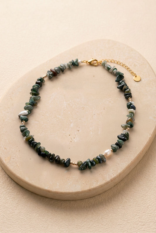 Vue d'ensemble du collier Câpre sur un support noir, détaillant les nuances de vert des pierres et le fermoir en acier inoxydable doré.