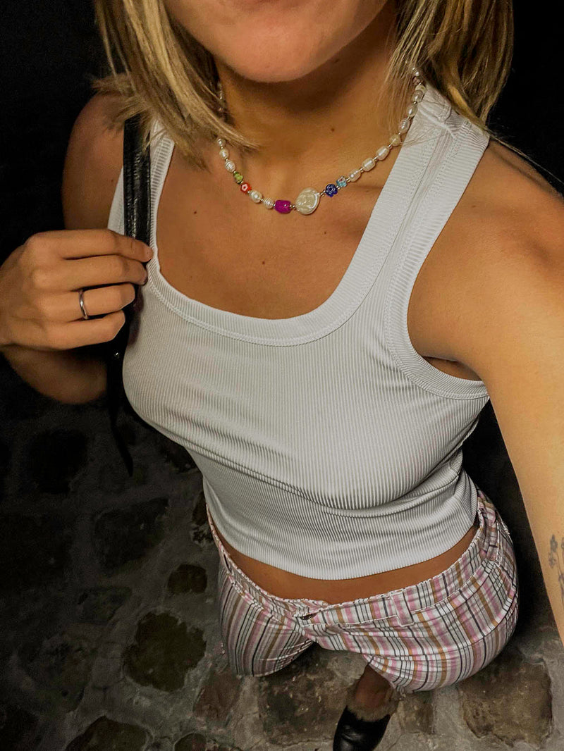 Femme portant le collier Arlequin Bourjeone, bijou fait main mêlant perles colorées, nacrées et fantaisie, au style ludique et raffiné.