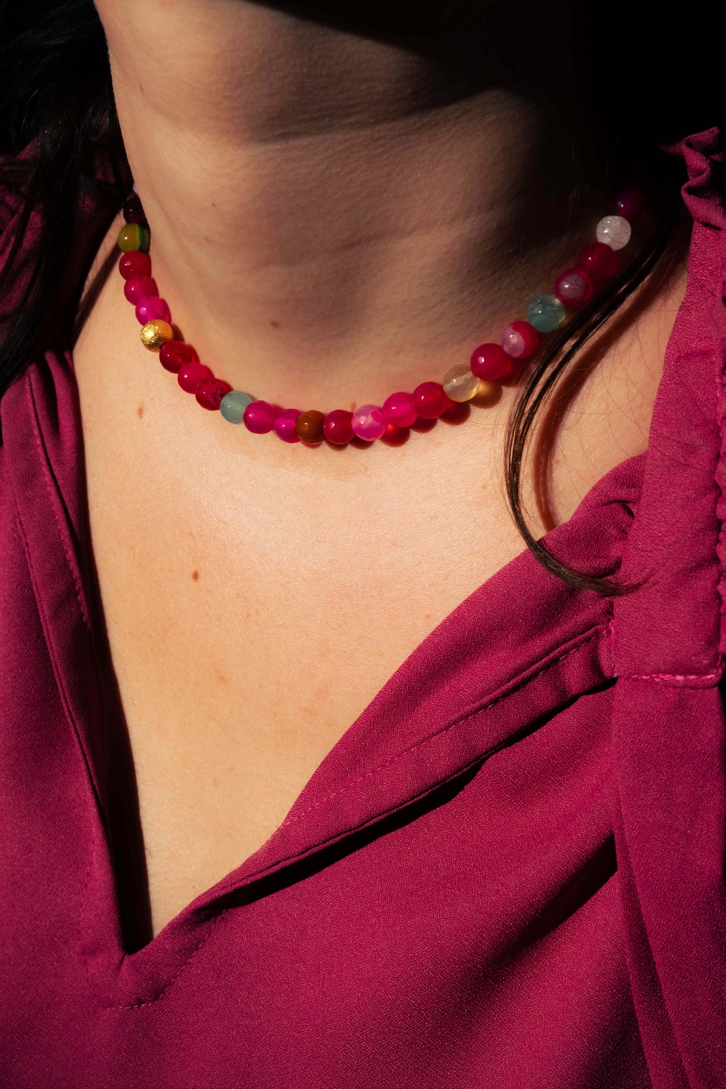 Collier Bourjeone en perles multicolores aux tons rose et framboise, photographié en lumière naturelle – collection Sucrée.