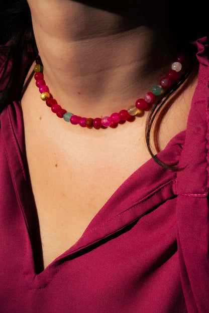 Collier Bourjeone en perles multicolores aux tons rose et framboise, photographié en lumière naturelle – collection Sucrée.