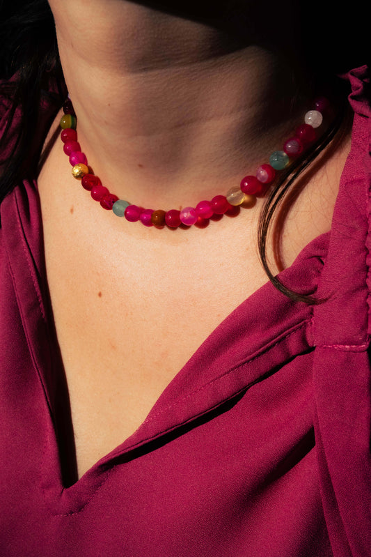 Collier Bourjeone en perles multicolores aux tons rose et framboise, photographié en lumière naturelle – collection Sucrée.