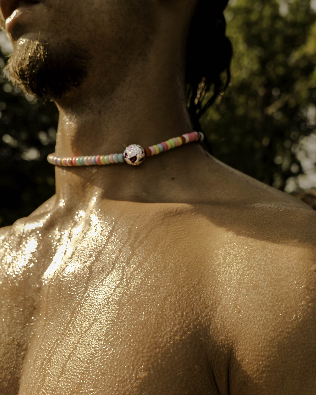 Homme portant le collier Bubble Gum Bourjeone, perles colorées et éclatantes sur peau dorée au soleil.