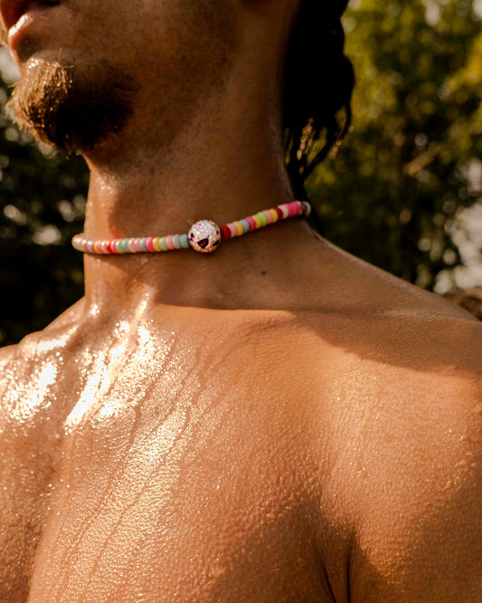 Homme portant le collier Bubble Gum Bourjeone, perles colorées et éclatantes sur peau dorée au soleil.