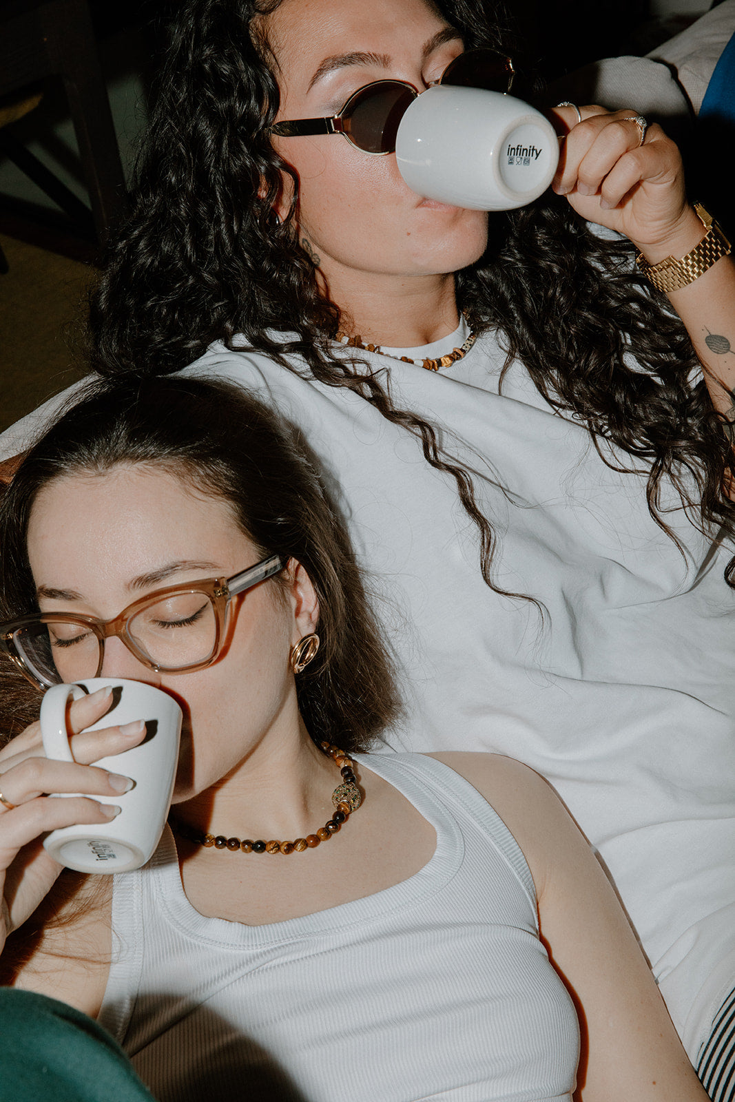 Portrait de femmes portant le collier Gravy avec débardeur blanc et tenant un mug, montrant les reflets de la perle strass au flash.