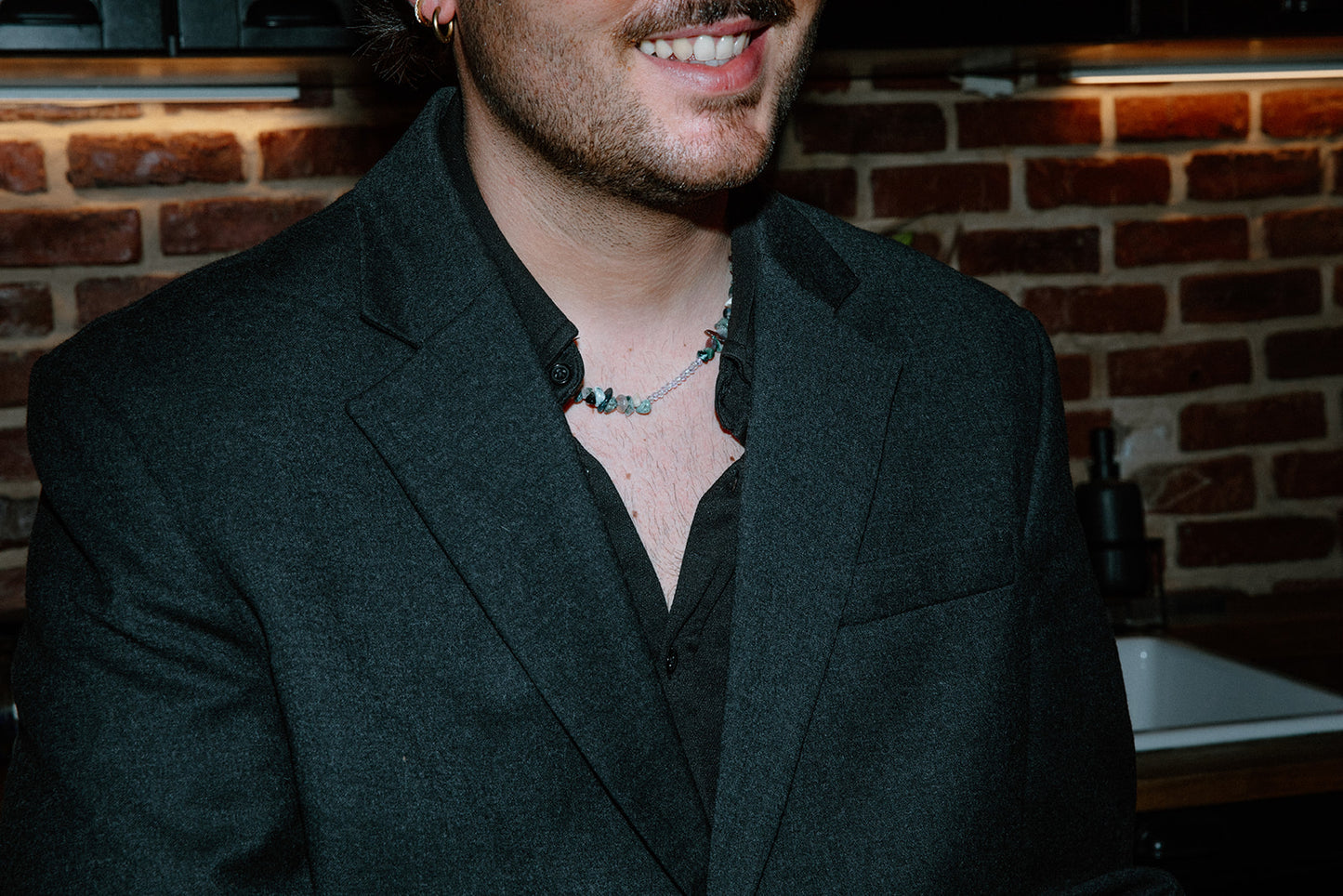 Portrait d'un homme portant le collier Pistachio, montrant l'éclat des perles vertes sur une tenue élégante.