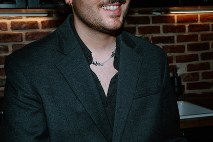 Portrait d'un homme portant le collier Pistachio, montrant l'éclat des perles vertes sur une tenue élégante.