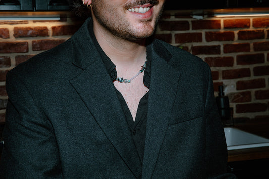 Portrait d'un homme portant le collier Pistachio, montrant l'éclat des perles vertes sur une tenue élégante.