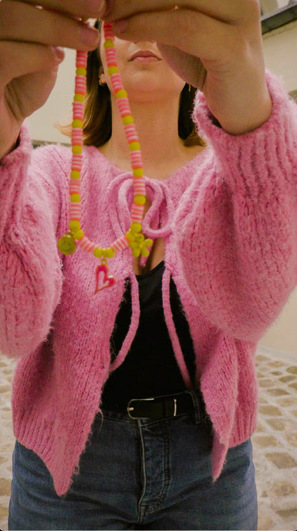 Femme tenant le collier Pink Lemonade Bourjeone, bijou fait main en perles roses et jaunes avec pendentif cœur, style pop et acidulé.