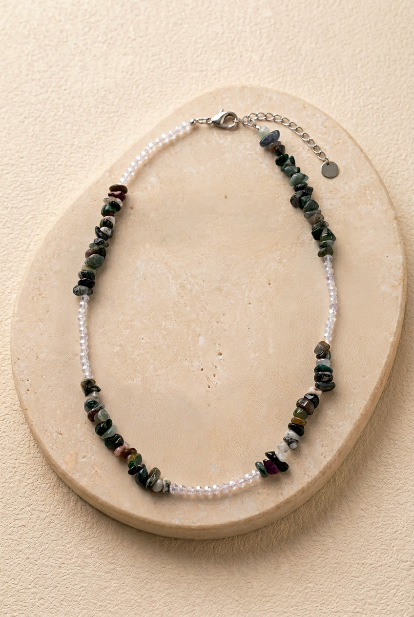 Collier Pistachio composé de perles chips vertes et perle d'eau douce, mis en scène avec des pistaches pour souligner sa teinte naturelle.