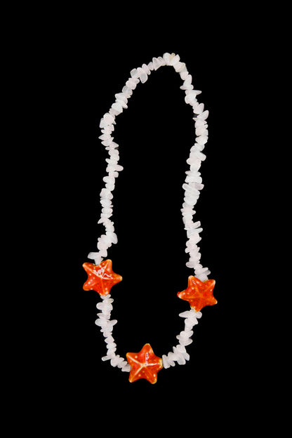 Léger comme une brise d’été — le collier Bourjeone mêle coquillages et éclats orangés pour un look frais et insouciant.