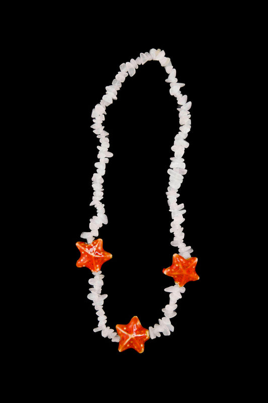 Léger comme une brise d’été — le collier Bourjeone mêle coquillages et éclats orangés pour un look frais et insouciant.