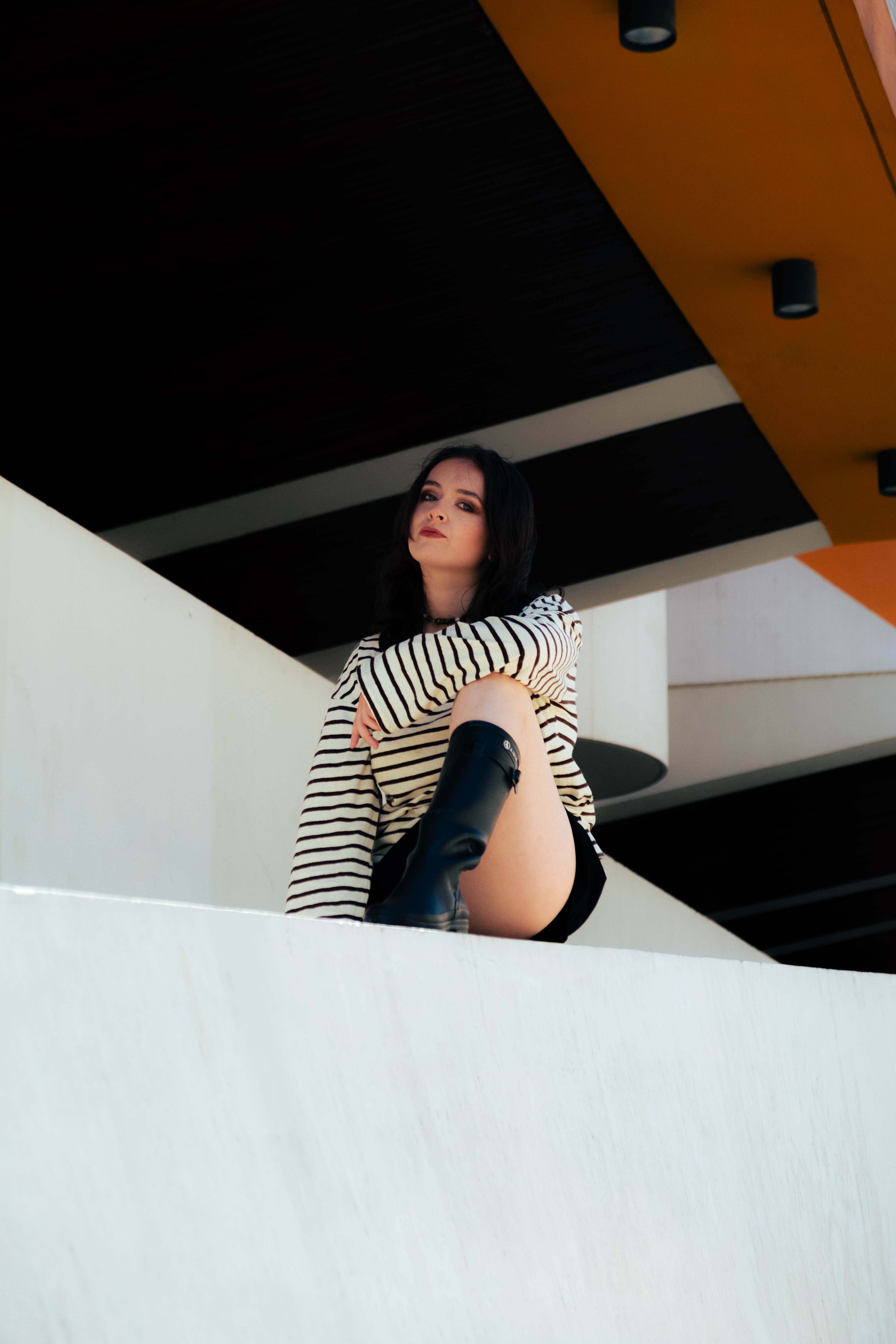 Femme en marinière posant dans une architecture moderne, portant les bijoux Bourjeone – collection Salée.