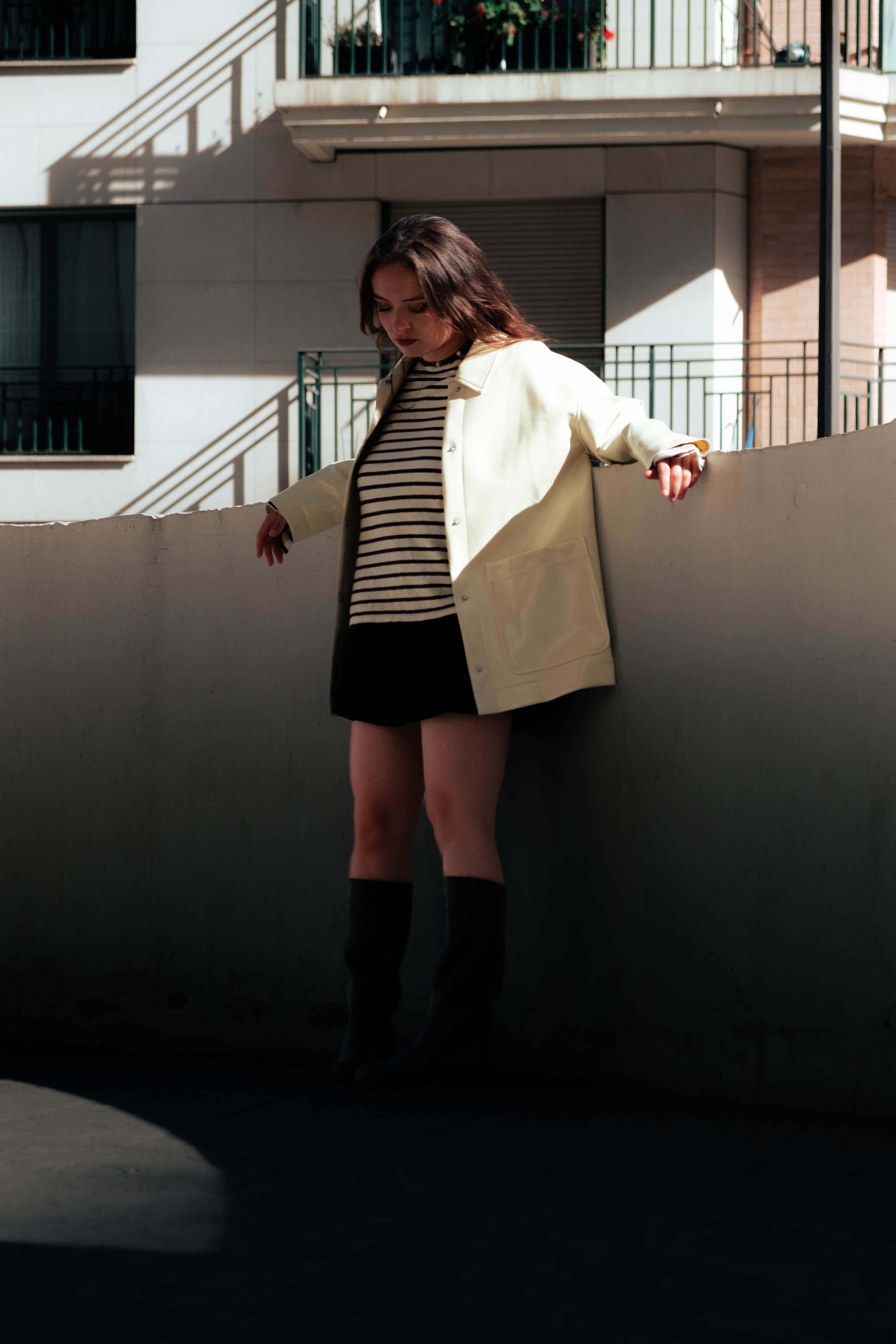 Femme vêtue d’une marinière et d’un manteau clair, photographiée en lumière naturelle avec les bijoux Bourjeone – collection Salée.